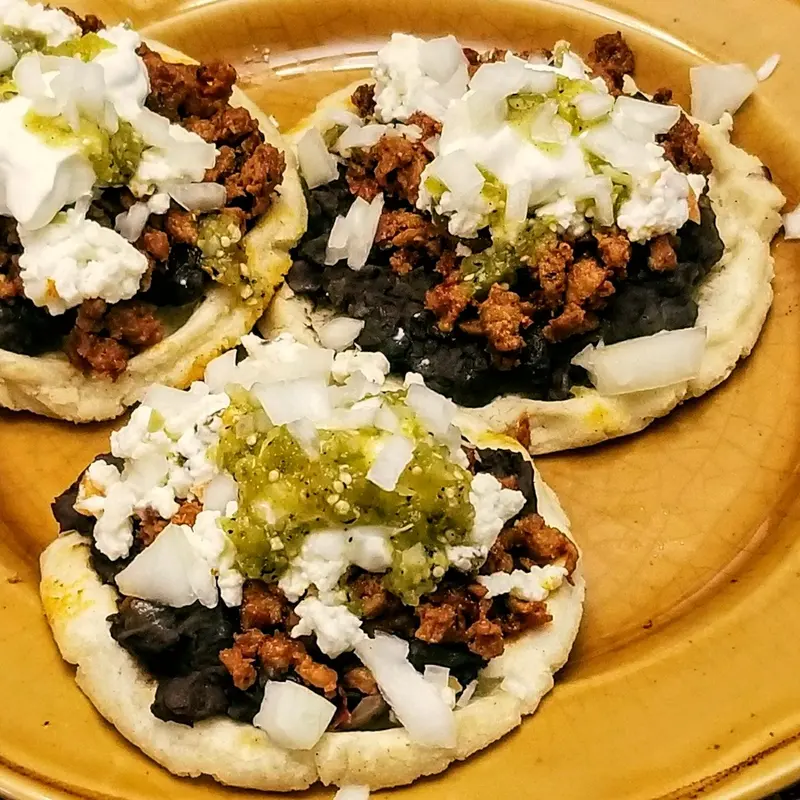Gorditas abiertas con guiso, frijol y queso fresco