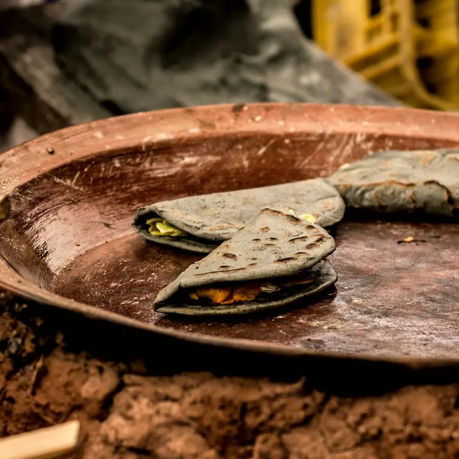 Quesadillas de maíz azul dorándose sobre un comal de barro